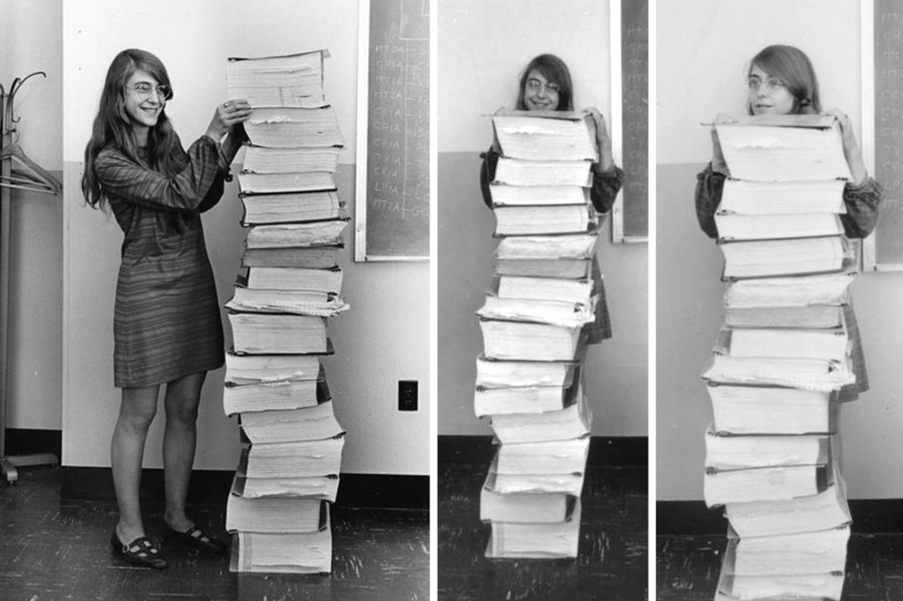 A young white woman with long hair and glasses standing next to and behind a pile of books as tall as her